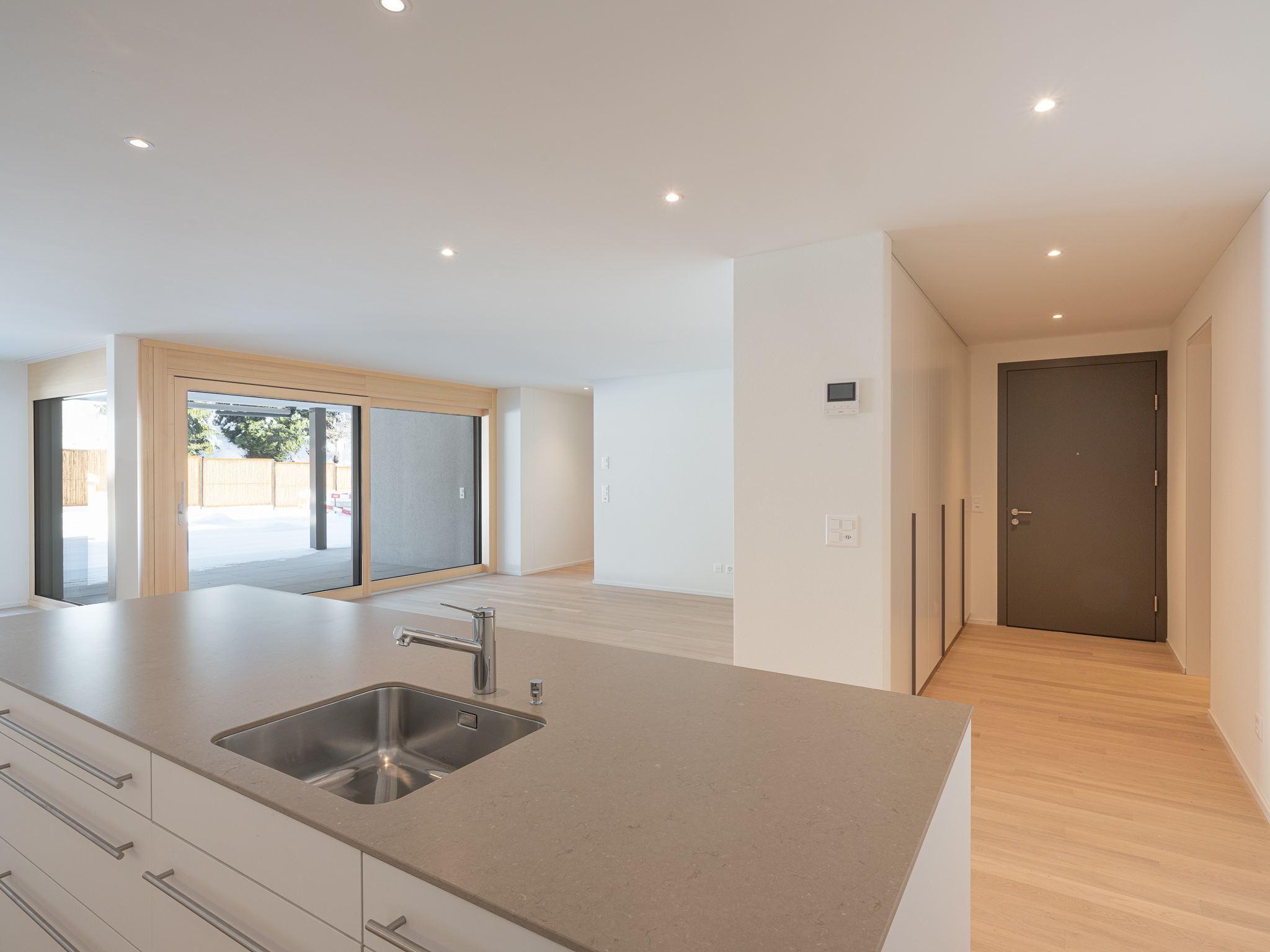 Offener Wohnraum mit Küche, Ess- und Wohnzimmer mit Ausblick auf einen Balkon.