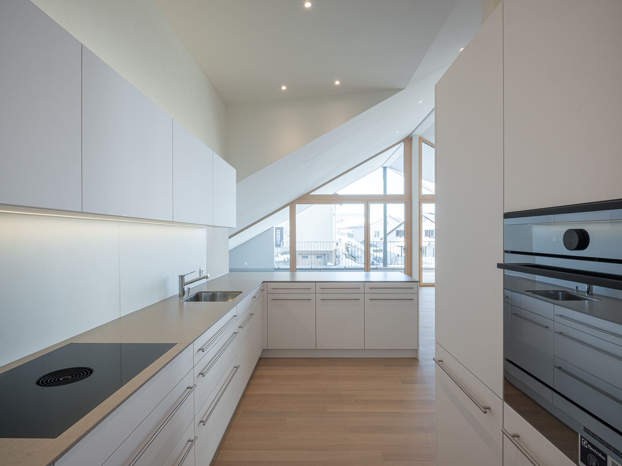 Ein offener Wohnraum mit Kochinsel, Esszimmertisch und Wohnzimmer.