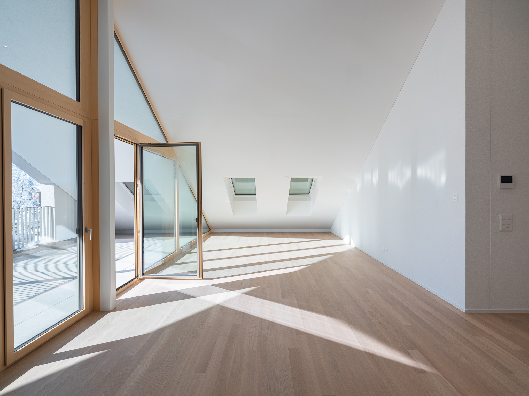 Eine offener Wohnraum mit Sofa und grossem Balkon.